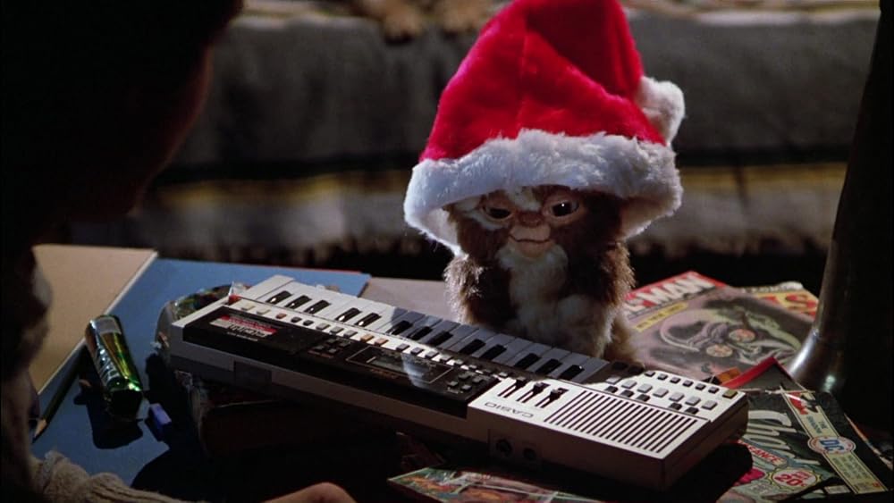 Gizmo wearing a Santa hat and sitting at a keyboard
